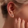 model wearing SIVYAA black solitaire princess cut diamond stud earrings, gold finish, for a daring elegant touch